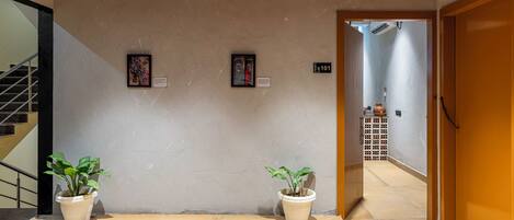 A hallway with two potted plants, a staircase, and a door leading to another room.