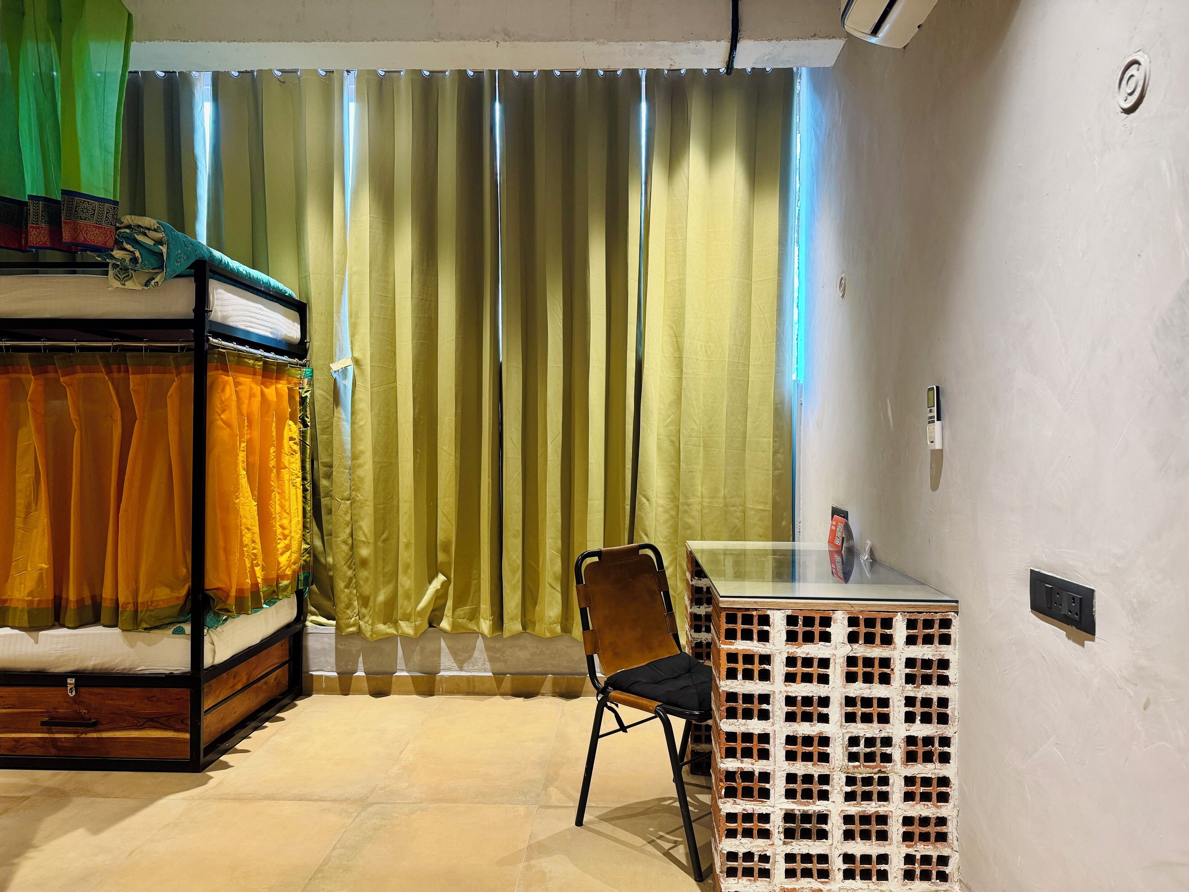 A room with a bed, a chair, a small table, and a window with curtains.