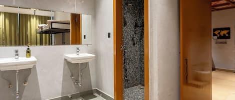 Ein Badezimmer mit zwei Waschbecken, einer Dusche und einer Holztür zu einem anderen Raum.
