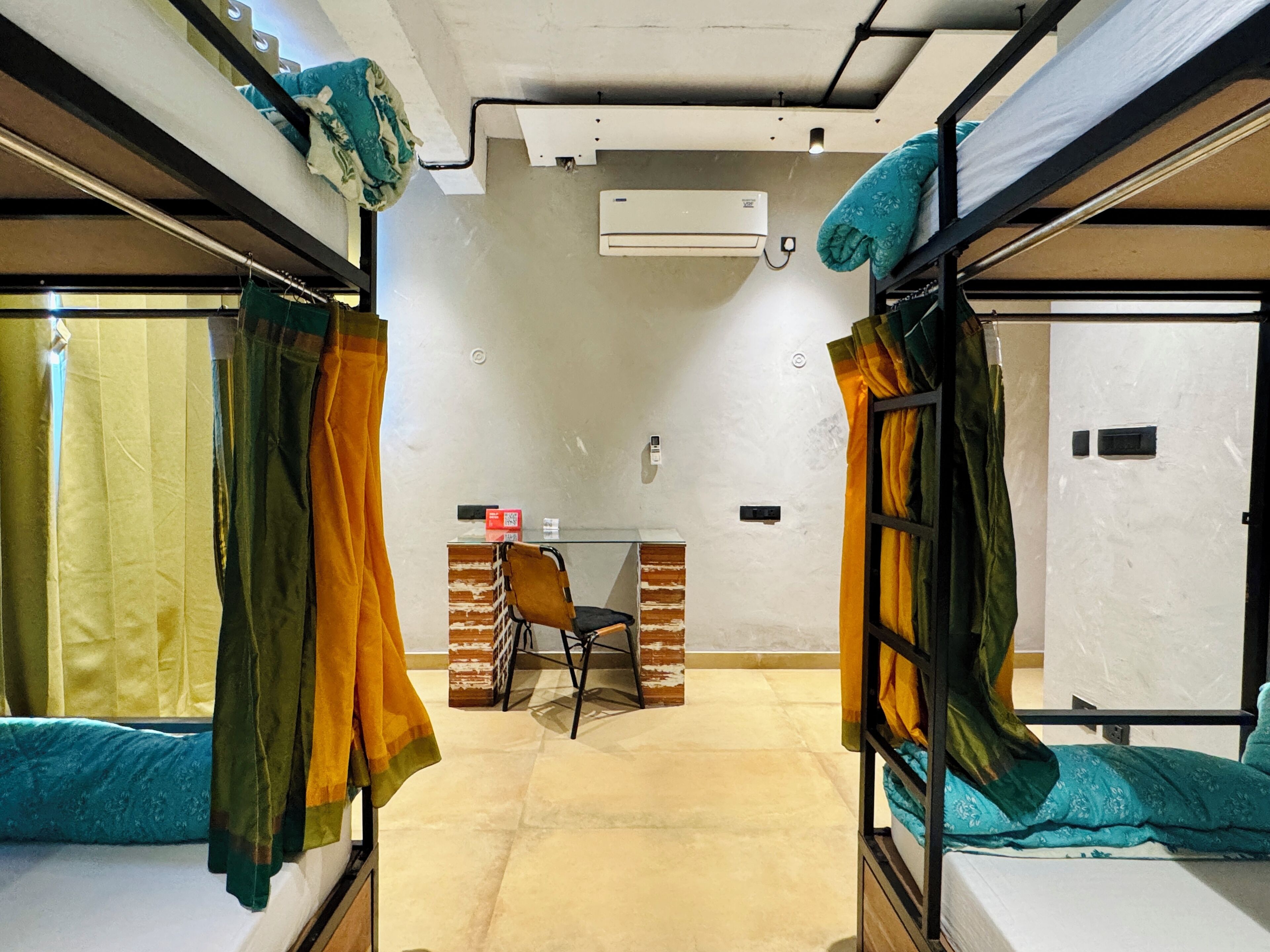 A dormitory room with bunk beds, a desk, and a chair.