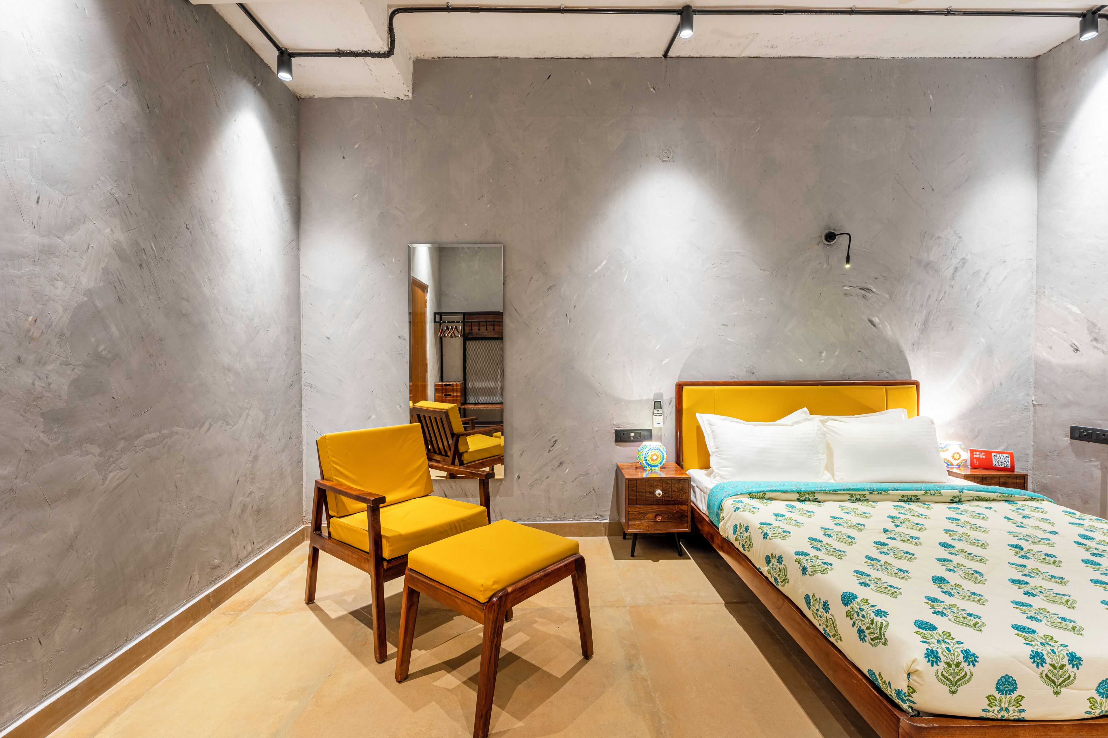A bedroom with a bed, a chair, a nightstand, and a mirror.