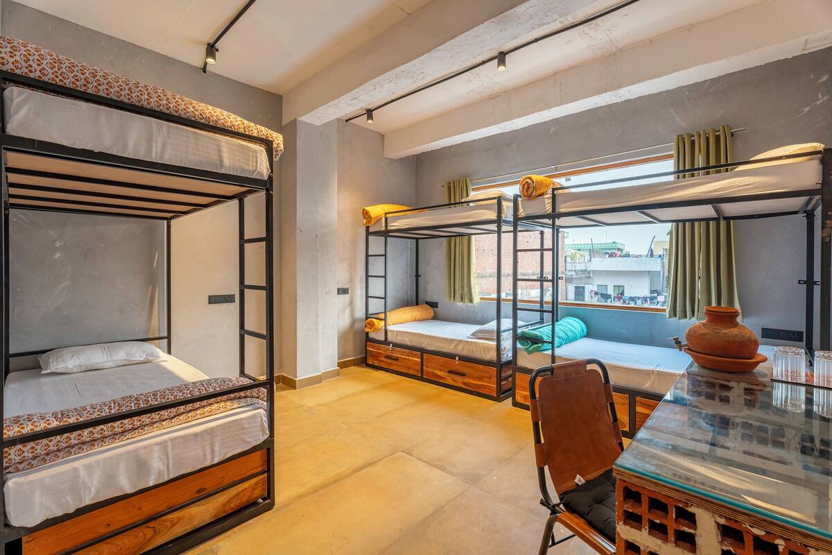 Une chambre avec deux lits superposés, un bureau en bois et une fenêtre avec des rideaux.