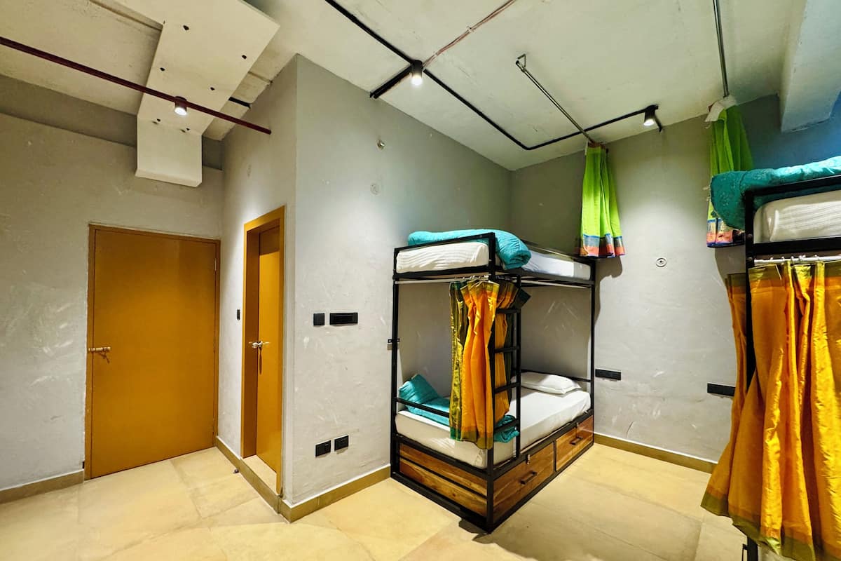 Une pièce avec des lits superposés, une porte et un luminaire au plafond.