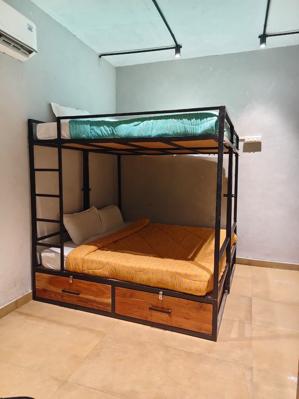 Un lit superposé avec une échelle, un tiroir en bois et un mur blanc.