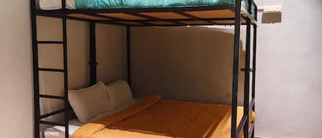 Una cama litera con escalera, un cajón de madera y una pared blanca.