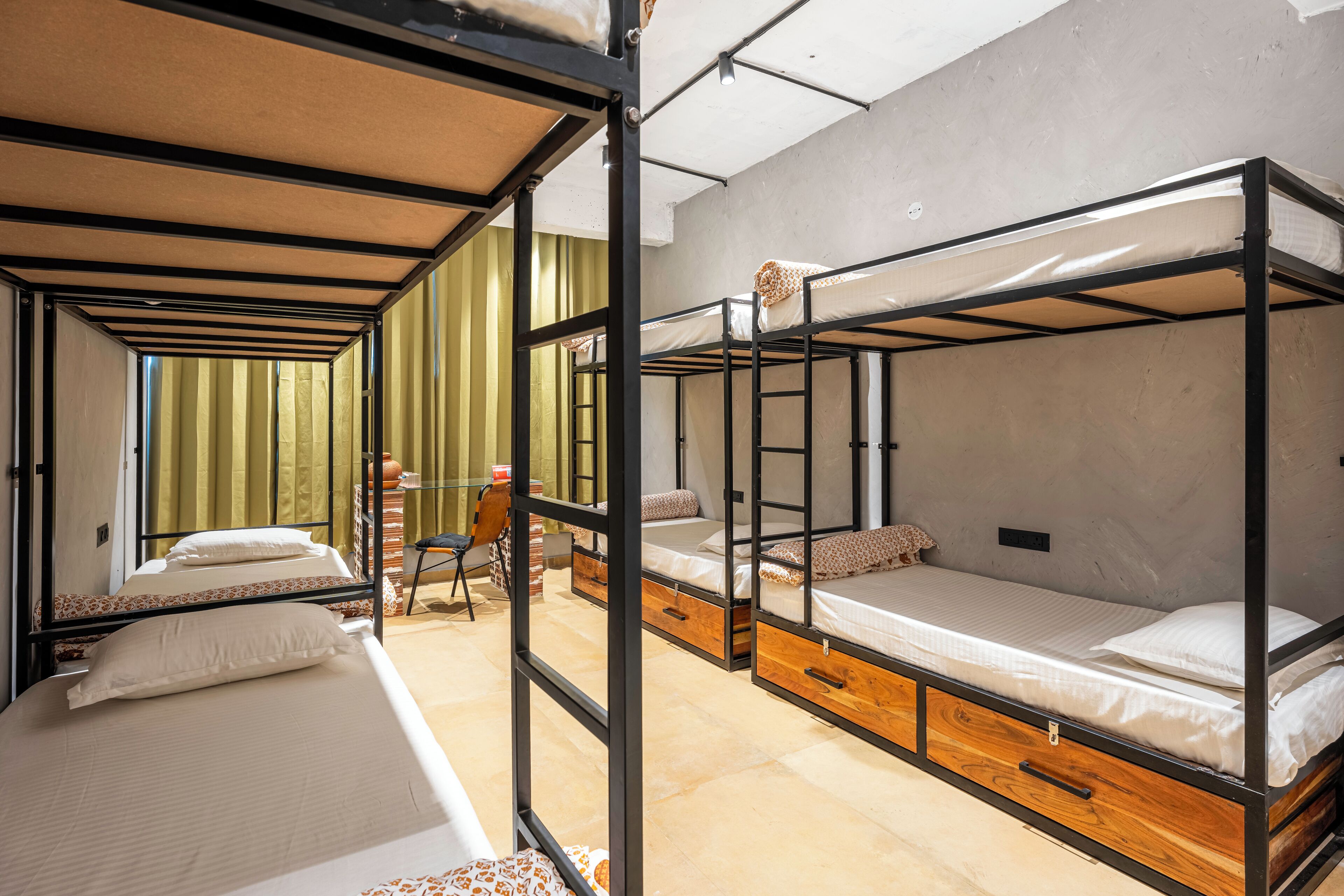 Un dormitorio con literas, cajones de madera y una ventana con cortinas.