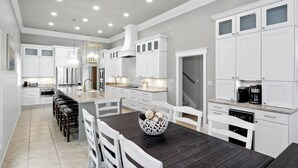 Una cocina moderna con armarios blancos, una mesa de comedor de madera oscura y una isla central.