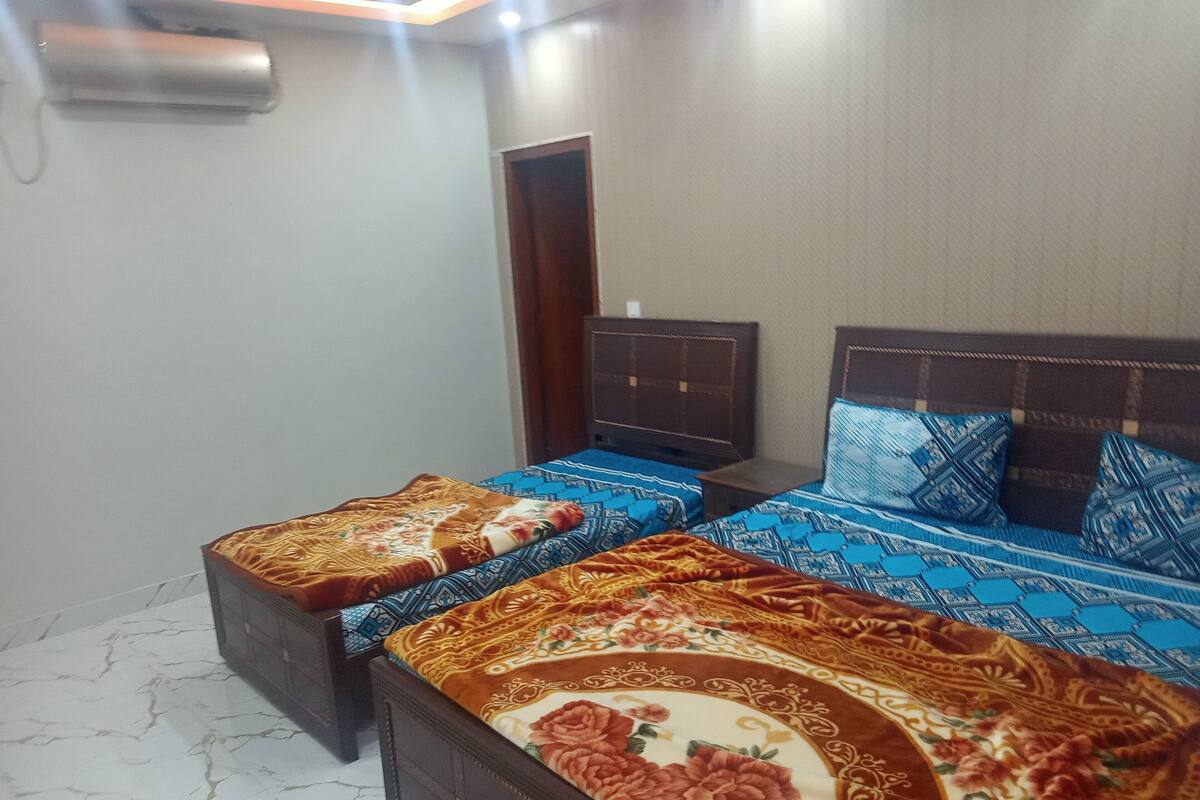 A bedroom with two beds, a wooden headboard, and a small bedside table.