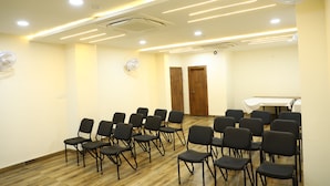 A conference room with rows of chairs, a table, and ceiling fans. - Hotel Singhnature (Khandwa)