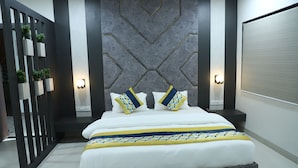 A modern bedroom with a large bed, geometric wall paneling, and two bedside lamps. - Hotel Singhnature (Khandwa)