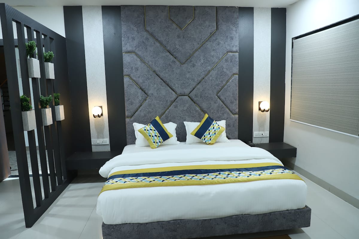 A modern bedroom with a large bed, geometric wall paneling, and two bedside lamps.
