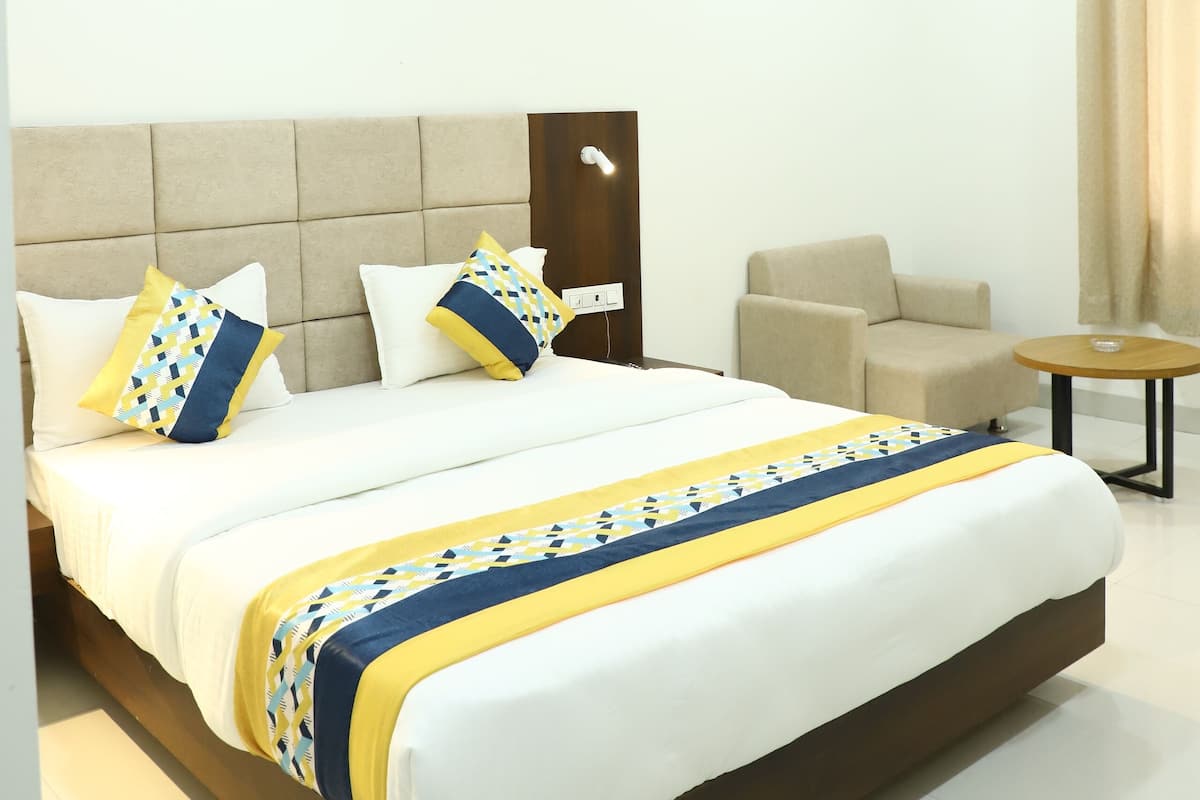 A modern hotel room with a large bed, a sofa, a small table, and a ceiling fan.