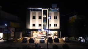 A multi-story hotel with a central entrance, multiple parking spaces, and a visible staircase leading to the entrance. - Hotel Singhnature (Khandwa)