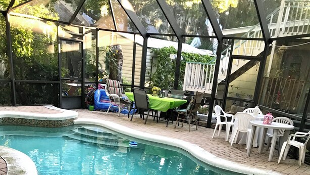 A swimming pool with a tiled edge, surrounded by a brick patio. There are plastic chairs and a table with a green tablecloth. - Historic home 2-bedroom upstairs pet friendly apartment w/ pool in St. Aug  (St. Augustine)