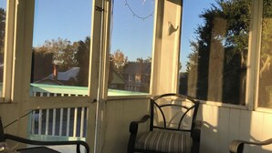 A porch with a chair and a table, a view of a house, and a clear sky. - Historic home 2-bedroom upstairs pet friendly apartment w/ pool in St. Aug  (St. Augustine)