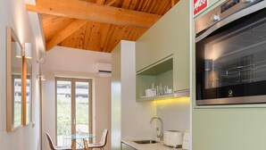 Une cuisine moderne avec des poutres en bois, un coin repas avec des chaises et une vue à travers une porte vitrée.