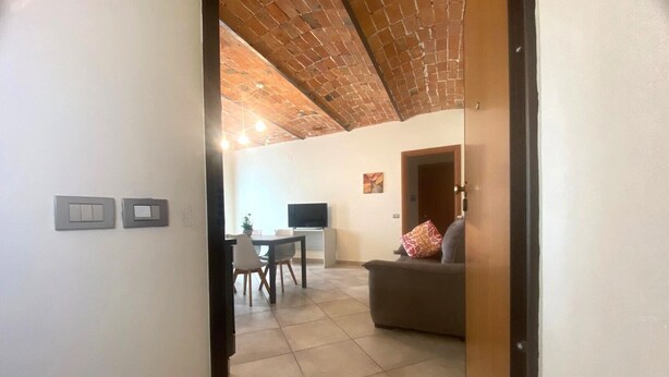 A spacious living area with a dining table and chairs, a sofa, and a television. - Ideal apartment for couple and family in the heart of Monferrato (Castell'Alfero)