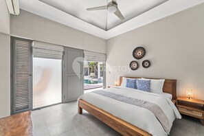 Relax in a spacious room with a large bed, bedside tables, and a ceiling fan, offering a luxurious setting with a pool access.