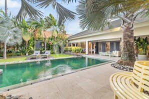 Relax by the serene pool surrounded by lush tropical plants and palm trees.