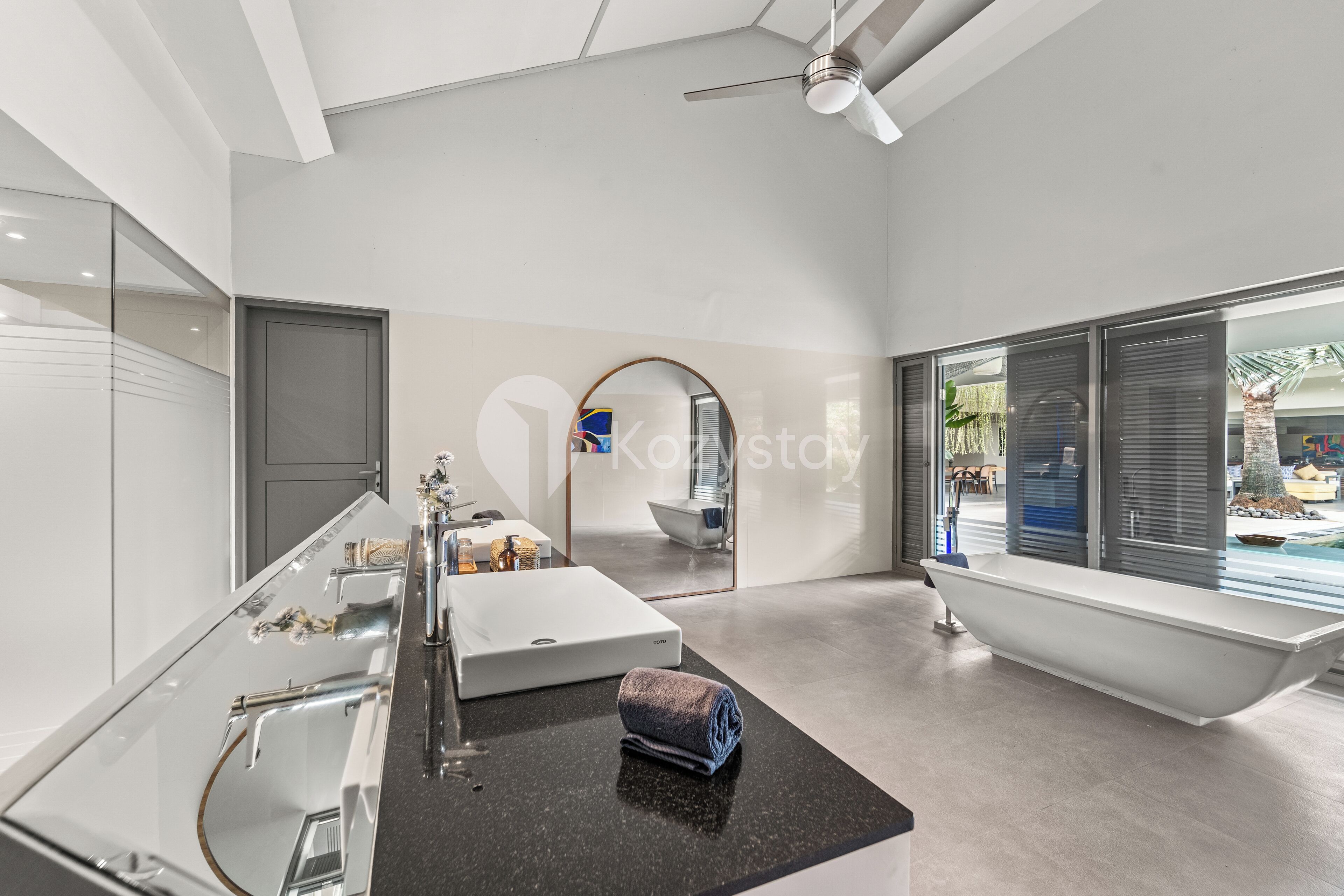 A modern bathroom with a large mirror, a bathtub, and a vanity with a sink.