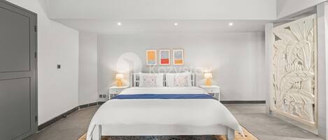 A modern bedroom with a large bed, a patterned rug, a wall-mounted air conditioner, and a decorative panel on the right.