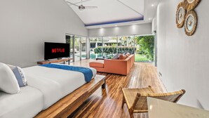 Un dormitorio moderno con una cama grande, televisión y vistas a un jardín.