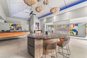 Enjoy cooking in this kitchen with a central island and sleek countertop, surrounded by a dining area with a round table and contemporary chairs.