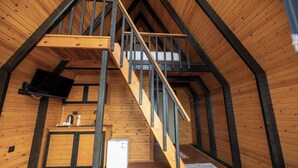 A wooden interior with a staircase, a small kitchenette, and a television. - Roseira Bungalov (Milas)