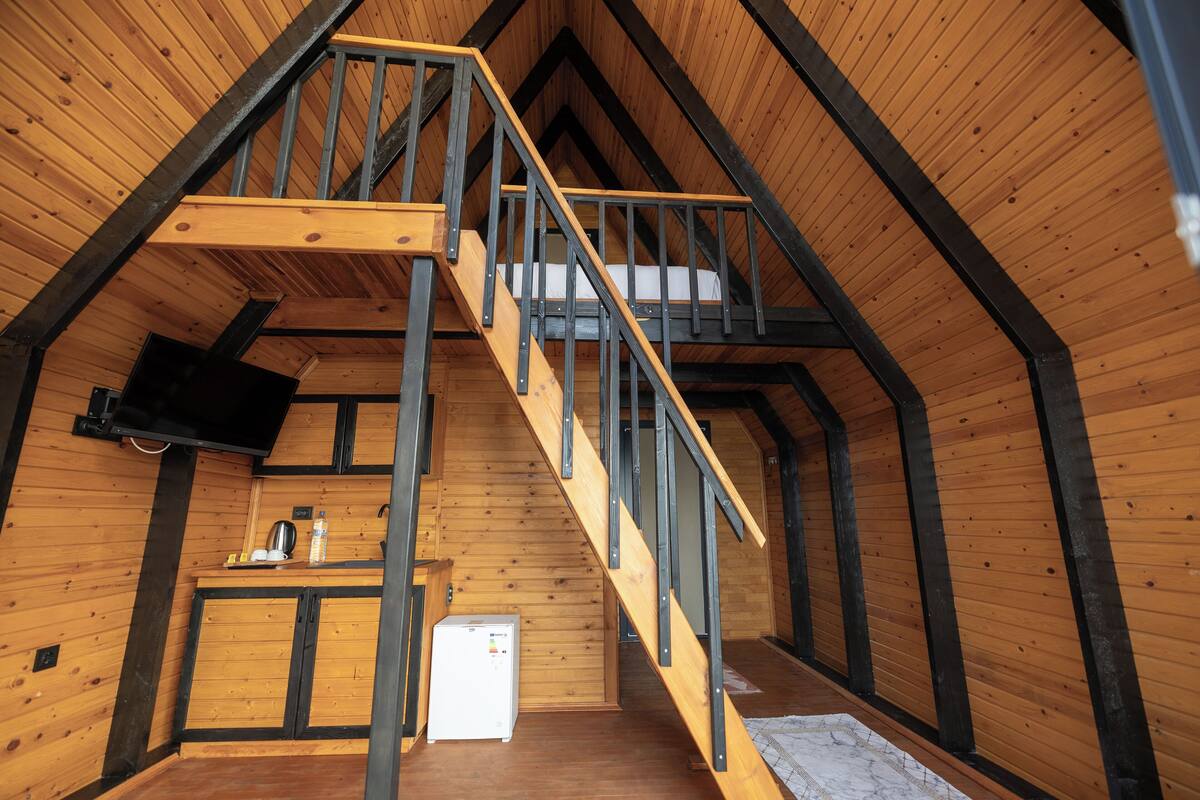 Un intérieur en bois avec un escalier, une petite cuisine et un téléviseur.