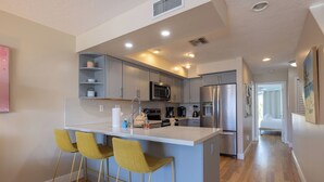 Una cucina moderna con isola centrale, sgabelli da bar ed elettrodomestici integrati.