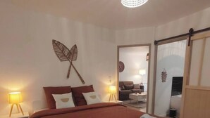 Une chambre moderne avec un grand lit, deux lampes de chevet, une décoration murale en forme de papillon et une porte coulissante donnant sur une autre pièce.