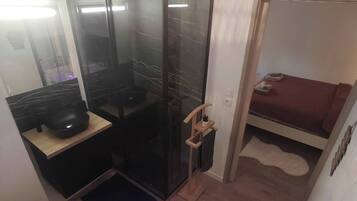 Een moderne badkamer met een glazen douchecabine, een badkuip met paars licht en een houten bankje.