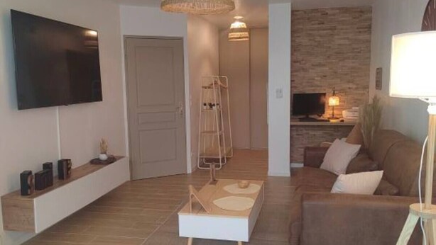 Un salon moderne avec un téléviseur à écran plat, un canapé marron, une table basse et une cheminée.