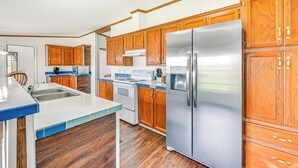 Una cocina con armarios de madera, un refrigerador de acero inoxidable, un lavamanos y una estufa.
