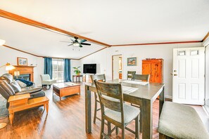 A spacious living room with a wooden dining table, leather sofa, and a fireplace. - 3 Mi to Green River Lake: Quiet Farmhouse w/ Yard (Campbellsville)