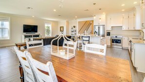 A spacious kitchen with white cabinetry, a wooden dining table, and a central island.