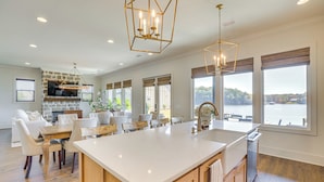 A spacious kitchen with a large island, wooden cabinets, and a stone fireplace. - Waterfront Home in Alex City, Near Auburn (Alexander City)