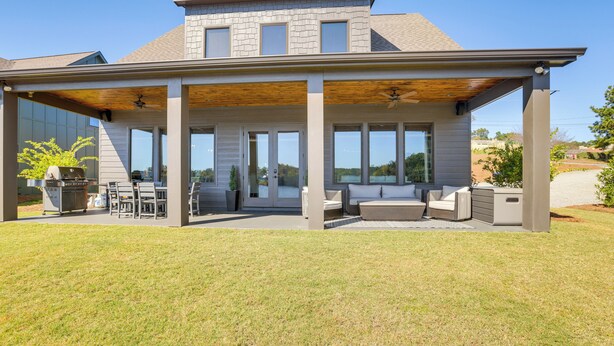 A modern house with a covered patio, outdoor seating, and a grill area. - Waterfront Home in Alex City, Near Auburn (Alexander City)