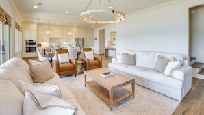 A spacious living room with a large white sofa, a wooden coffee table, and a dining area with a table and chairs. - Waterfront Home in Alex City, Near Auburn (Alexander City)