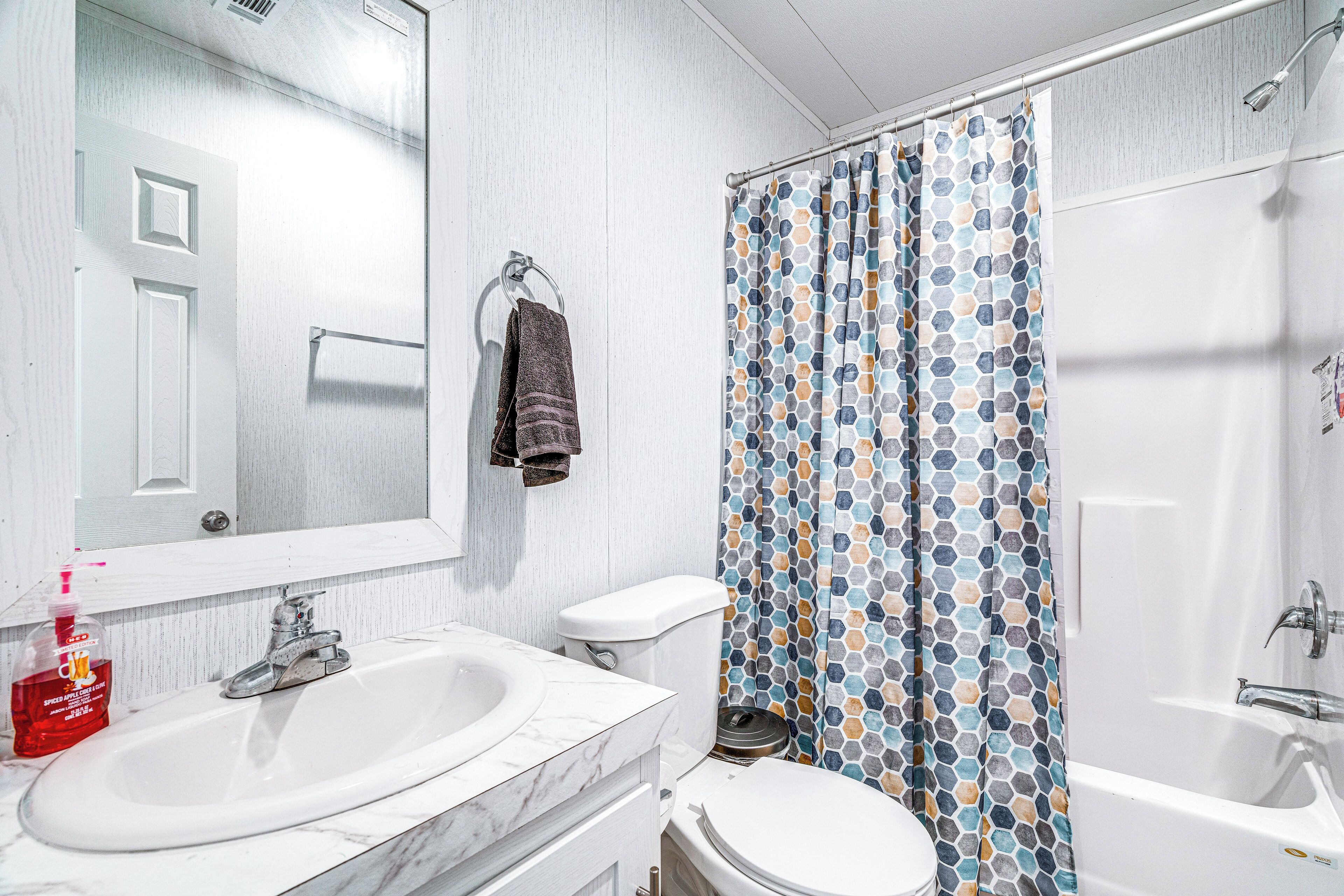 A bathroom with a white sink, toilet, and bathtub. There is a mirror above the sink and a towel hanging on the wall.