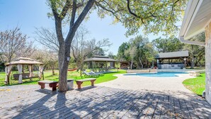A wooden deck with picnic tables and a gazebo, a swimming pool, and a covered seating area. - Expansive Bertram Retreat w/ Pool, on 28 Acres! (Bertram)