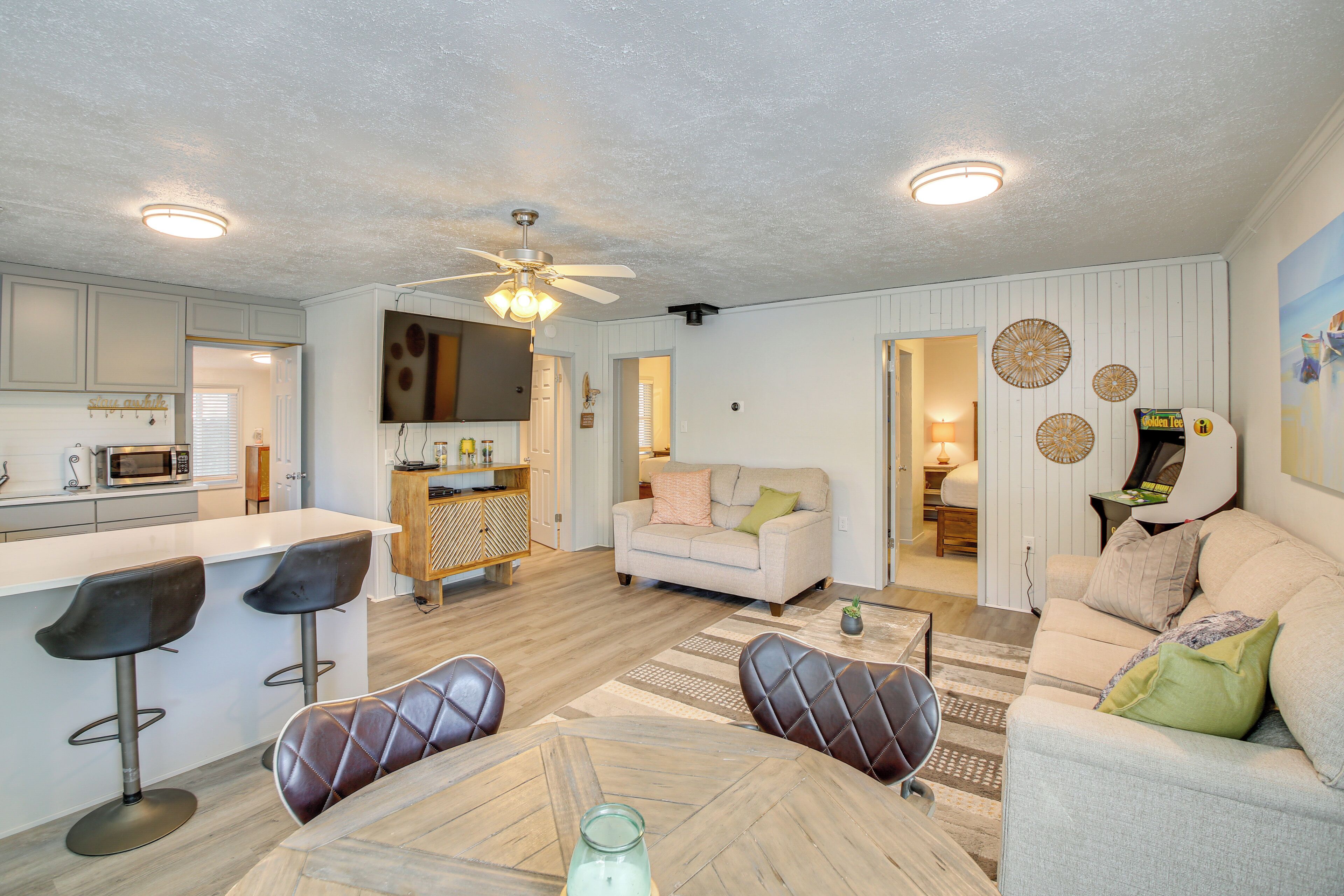 A modern kitchen with a bar area, a living room with a sofa and chairs, and a dining area with a table and chairs.