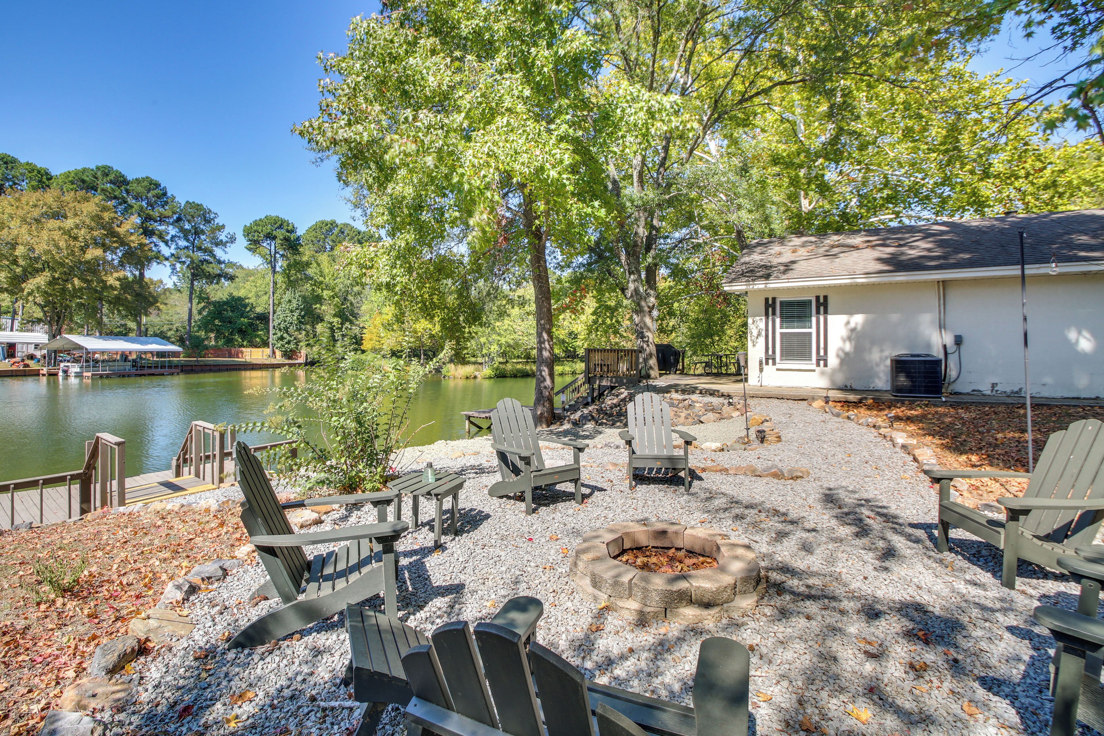 Une terrasse au bord du lac, avec des fauteuils Adirondack, un foyer et un petit bâtiment.