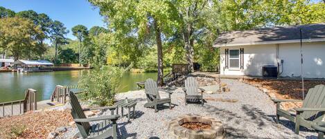 Une terrasse au bord du lac, avec des fauteuils Adirondack, un foyer et un petit bâtiment.