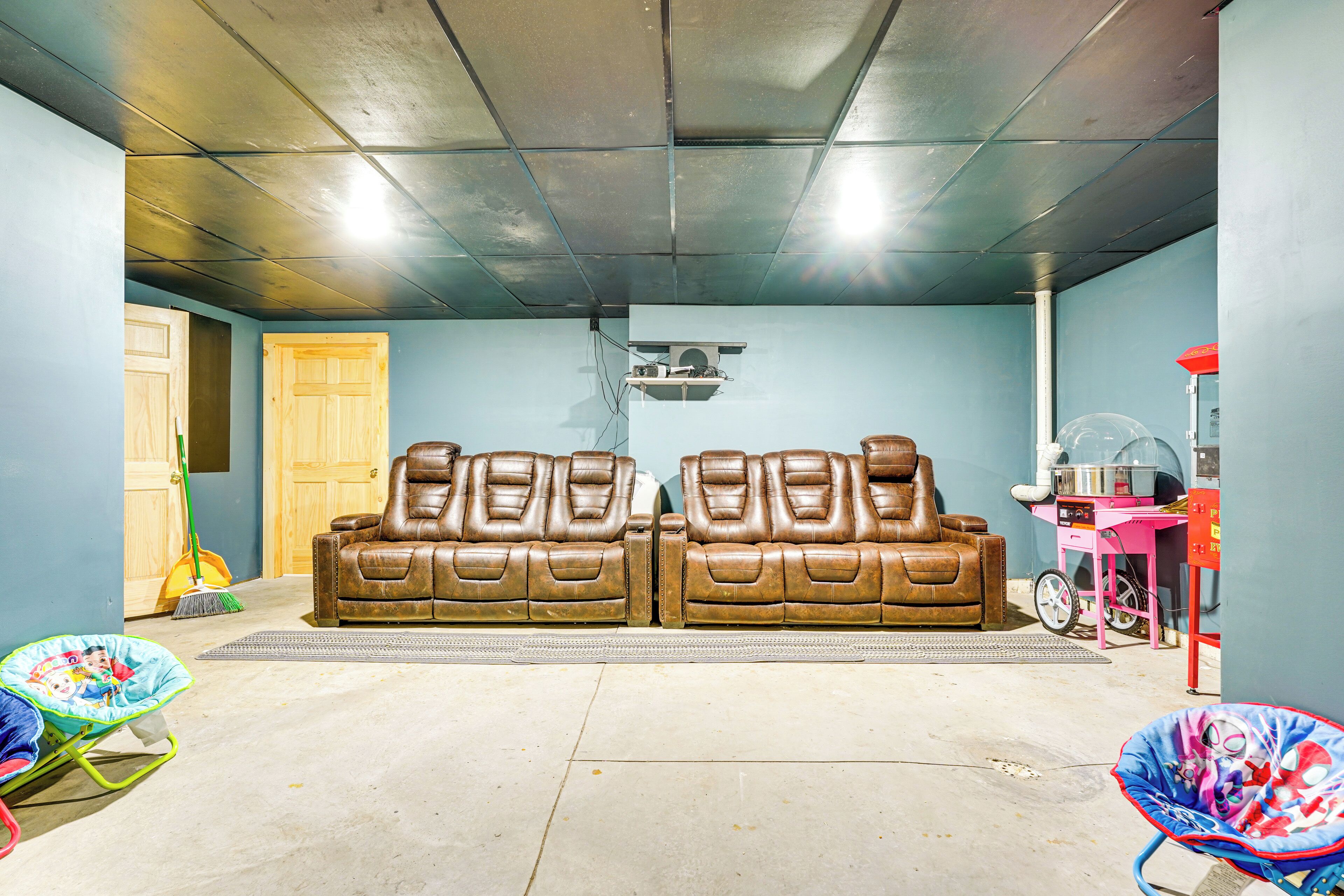 A room with two leather sofas, a ceiling fan, and a pink cart with a grill.