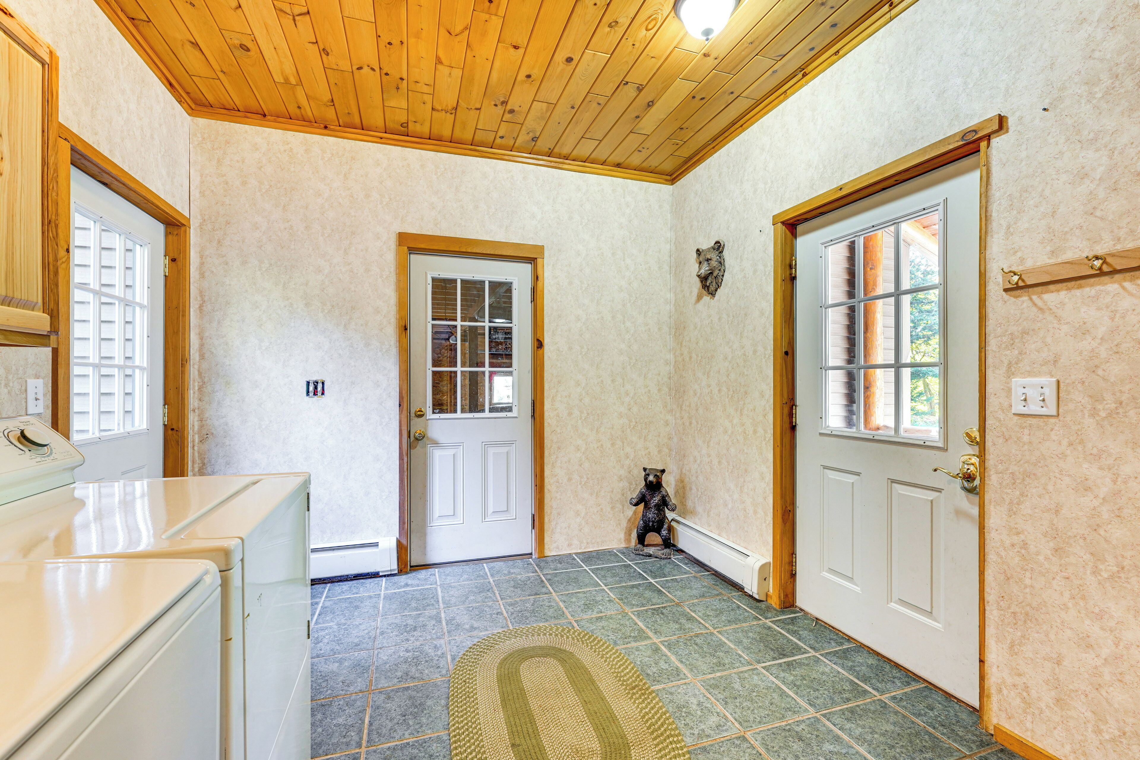 Un couloir avec un plafond en bois, un tapis à motifs et une porte ornée d’une représentation d’un ours.