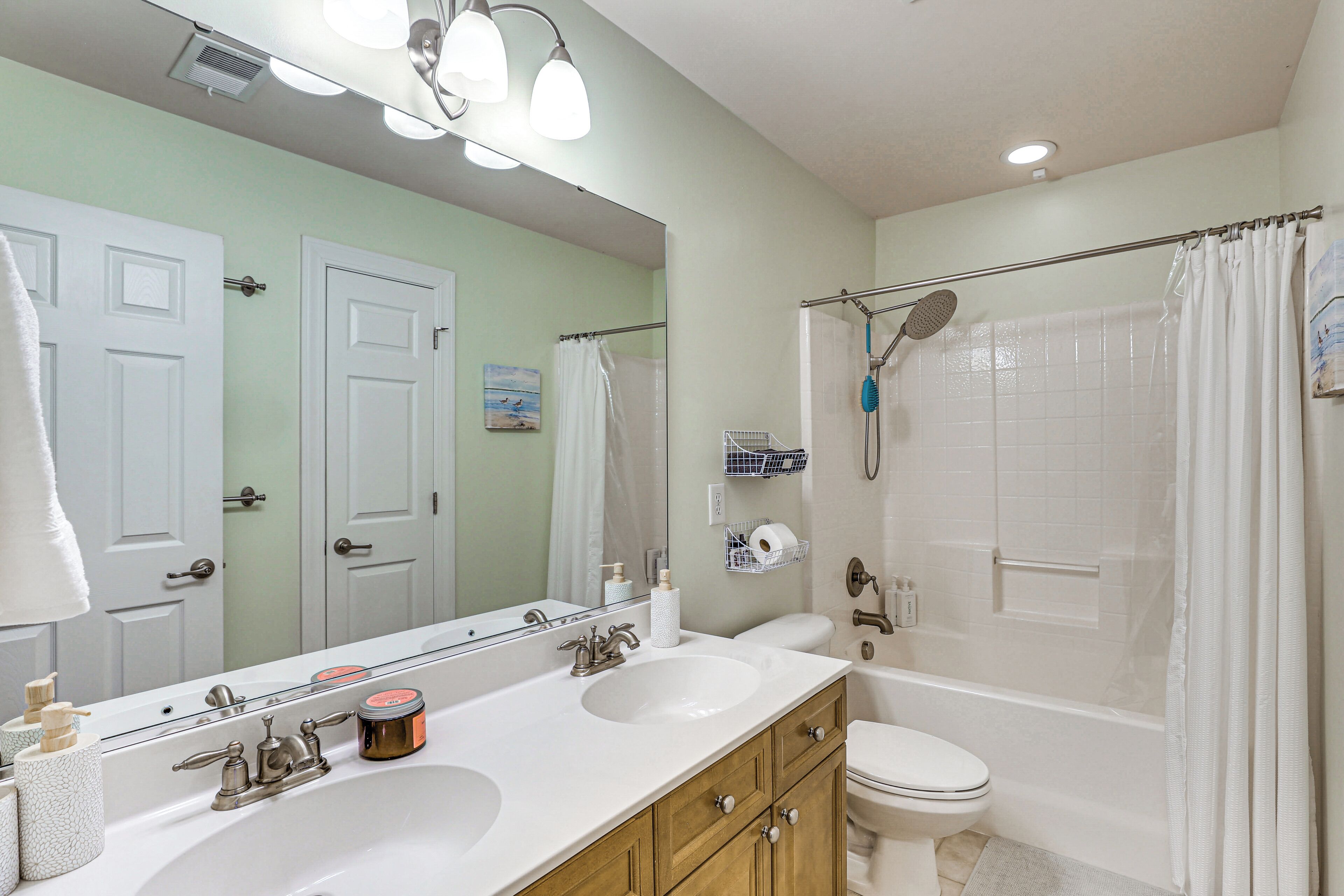 A bathroom with two sinks, a toilet, a shower, and a large mirror.