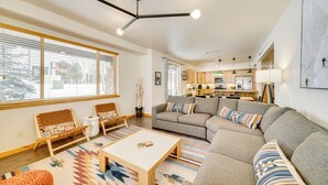 A modern living room with a sofa, coffee table, and a dining area. - Downtown WP Condo w/ Pool: Steps to Concert Venue! (Winter Park)