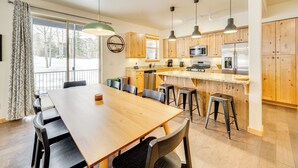 A modern kitchen with wooden cabinets, a central island, bar stools, and pendant lighting. - Downtown WP Condo w/ Pool: Steps to Concert Venue! (Winter Park)