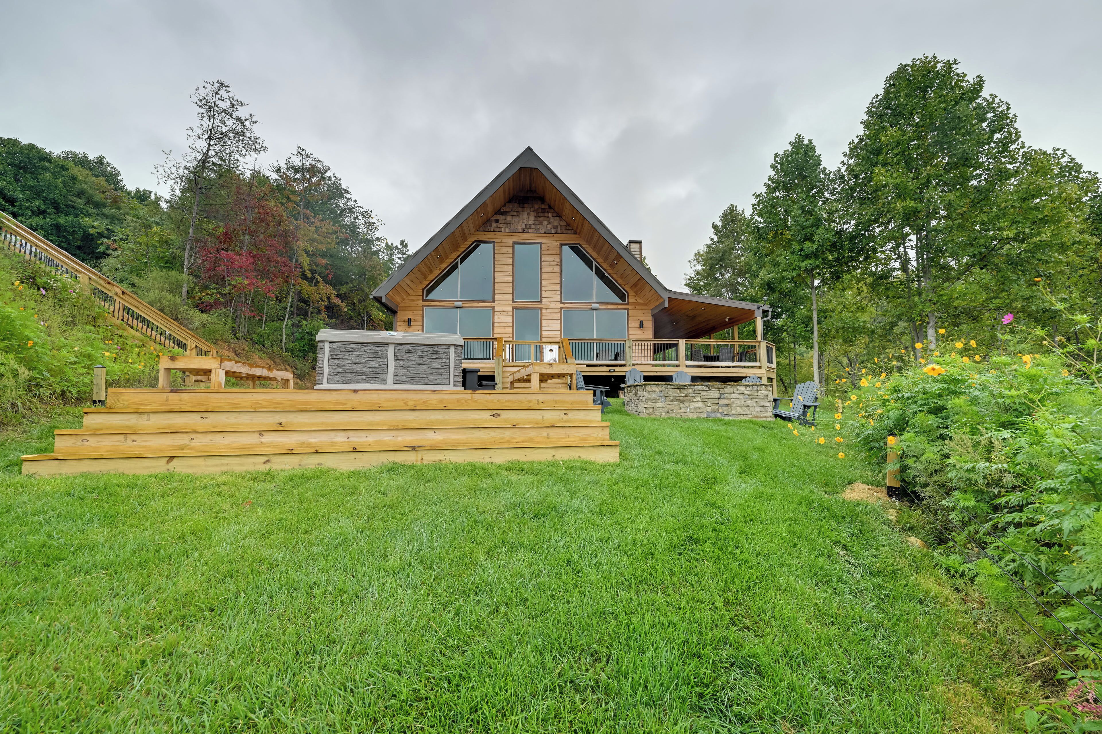 A large, modern house with a prominent wooden structure, a stone foundation, and a large glass window.